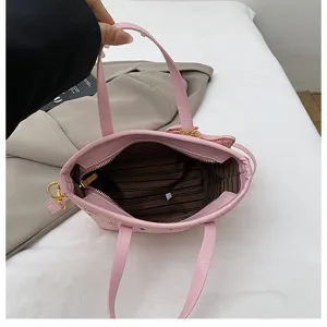 Pink leather bucket bag with top handles, zipper closure and striped interior lining.