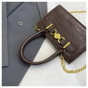 Bruine handtas met krokodillenprint, gouden ketting en elegante metalen sluiting als detail.