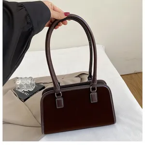 Nahaufnahme der retro braunen Samt-Achseltasche mit Kontrastnähten und Metallbeschlägen.