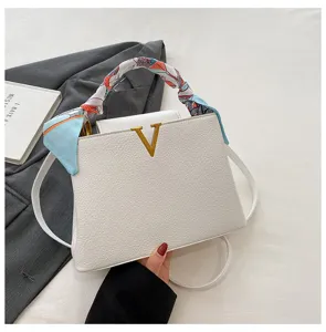 Detail view of the white litchi pattern leather handbag with metal V logo and silk scarf.