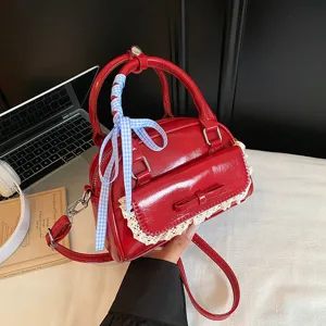 Stylish red patent leather handbag with lace trim and bow, versatile crossbody bag for women.