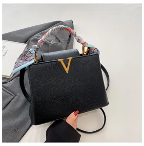 Black pebbled leather handbag with gold V logo, chic silk scarf handle, and shoulder strap.