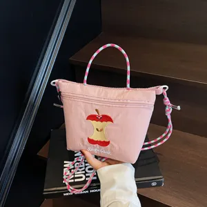 Cute pink nylon shoulder bag with colorful braided handle and apple core embroidery design.