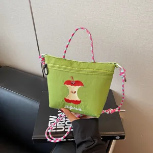 Green nylon crossbody bag with cute bitten apple embroidery and colorful woven straps for daily use.