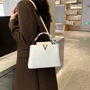 Elegant white litchi pattern leather handbag with gold V clasp and chic scarf for women.
