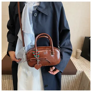 Nahaufnahme der retro braunen Bowling-Handtasche mit süßer Schleife und Perlenanhänger.