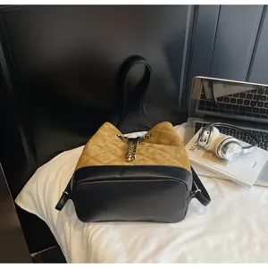 Vista dettagliata della borsa a secchiello elegante in camoscio con coulisse a catena.