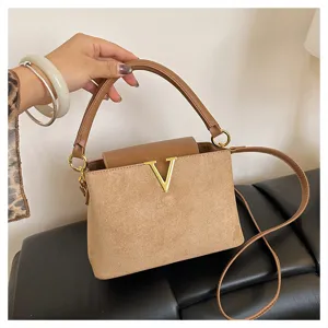 Women brown suede leather crossbody shoulder bag with metal V logo and top handle.