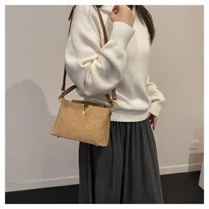 Detailed view of the retro brown suede shoulder bag with metallic V clasp worn by model.