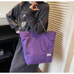 Detailed shot of a purple plaid tote bag featuring thick black and white rope shoulder straps.