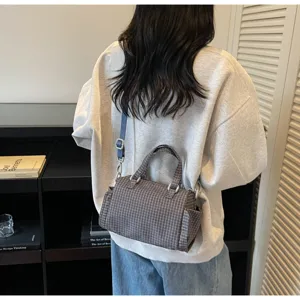 Gedetailleerd overzicht van stijlvolle geruite crossbody tas gedragen door model, dagelijks.