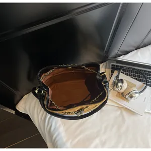 Dettaglio interno elegante borsa a secchiello da donna con ampio spazio e catene.