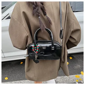 Schwarze Lackleder-Bowlingtasche Detail mit einzigartigem Perlenanhänger und Griff.