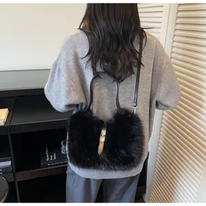 Black plush handbag detail, soft faux fur texture with metallic clasp and leather strap.