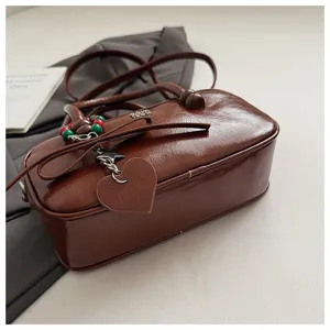 Detailansicht der vintage braunen glänzenden Bowlingtasche mit eleganter Schleife und Herz-Anhänger.