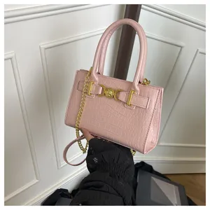 Roze handtas met krokodillenmotief, handvatten en gouden ketting, stijlvol detailoverzicht.