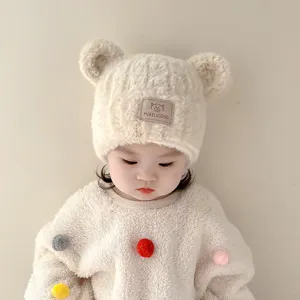 Close-up detail of cute baby plush bear ear winter hat with soft fleece material and patch.