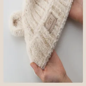 Close-up detail of cute plush bear ear baby winter hat, showing soft fabric texture and label.