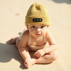 Close-up detail of the kids yellow knit beanie featuring a chic patch and warm woolen fabric.