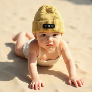 Cute baby wearing a yellow knit beanie hat on beach, detailed view of cute winter warm cap.