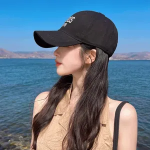 Close-up detail of the black cotton baseball cap worn outdoors, featuring stylish embroidery.