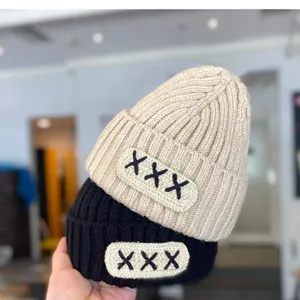 Infant knitted beanie detail shot, cute wool winter hat with embroidered patch design.
