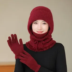 Close-up detail of winter warm knitted hat with integrated scarf and matching gloves in red.