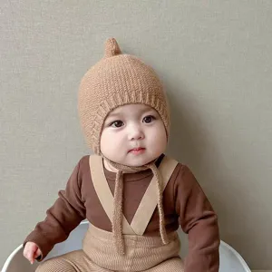 Vue detaillee du bonnet bebe en tricot avec joli noeud pour l'hiver et brides chaudes.