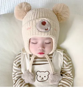 Cute baby winter knit hat with bear ears and plush pom poms. Warm earflap beanie for infants.