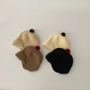 Close-up of cute baby knit earflap hats with pom-poms in four solid colors, cozy details.