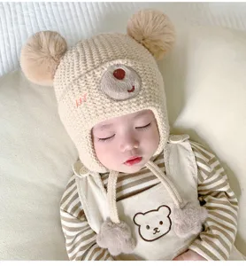 Baby winter knit hat with bear ears and pom poms, cute infant earflap beanie detail.