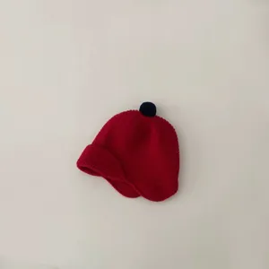 Cute kids warm knitted hat with earflaps and top pompom, solid red winter beanie.