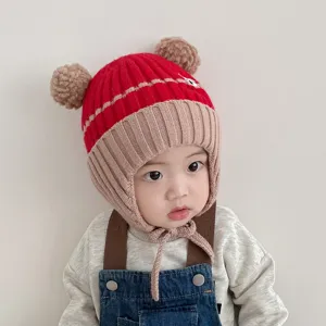 Detailed view of baby winter knit earflap hat with cute pom-pom ears and warm lining.