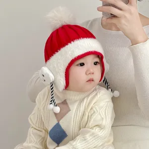 Close-up of the adorable baby winter hat featuring soft red knit and fluffy white earflaps.