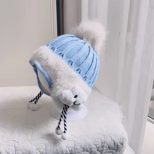 Cute baby winter knitted hat with earflaps, soft plush lining, and warm pom-pom design.