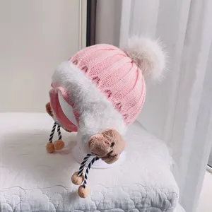 Cute pink baby winter knitted hat with earflaps, soft pom-pom and warm fleece lining for infants.