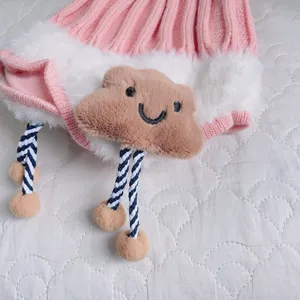 Cute baby winter knit hat detail, soft plush brim and sweet smiling cloud patch with pom-poms.