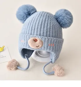 Cute baby winter knitted earflap hat with double pom-poms and lovely bear face detail.