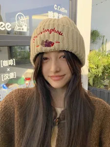 Detailed view of the cozy beige knitted beanie featuring cute bear embroidery and stylish text.