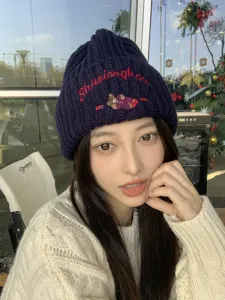Cute cartoon bear embroidered knit beanie hat detail view, warm winter cozy fashion style.