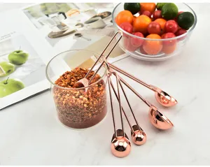Rose gold measuring spoons set stainless steel kitchen baking tools with clear scale marks.