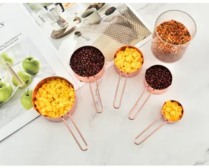 Detailed view of rose gold stainless steel measuring cups with wire handles for baking.