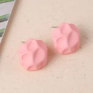 Detalle de pendientes de botón de acrílico geométrico rosa irregular, diseño caramelo.