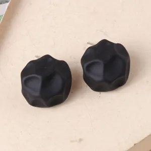 Primer plano detallado de pendientes geométricos negros irregulares únicos con textura mate.