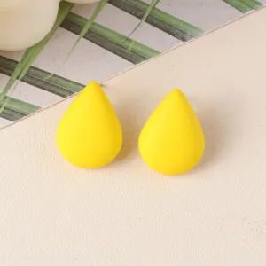 Close-up detail of minimalist yellow teardrop acrylic stud earrings with smooth matte finish.