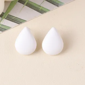 Close-up detail shot of minimalist white teardrop acrylic stud earrings, smooth texture.