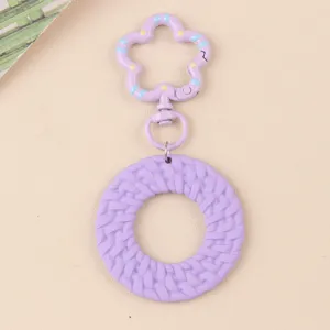 Vue détaillée du porte-clés en acrylique rond violet avec fermoir fleur et texture tissée.