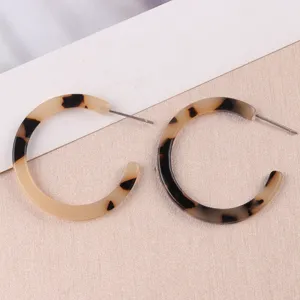 Gros plan détaillé des élégantes boucles d'oreilles créoles C en acétate écaille.