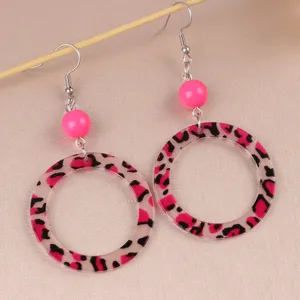 Close-up detail shot of vintage leopard print acrylic hoop earrings featuring bright pink beads.