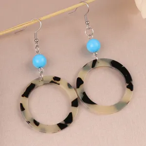 Detailed shot of retro geometric earrings with blue beads and tortoise shell acrylic rings.
